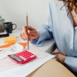Una mujer está calculando a mano cuando podría hacer facturas electrónicas con ERP QF.